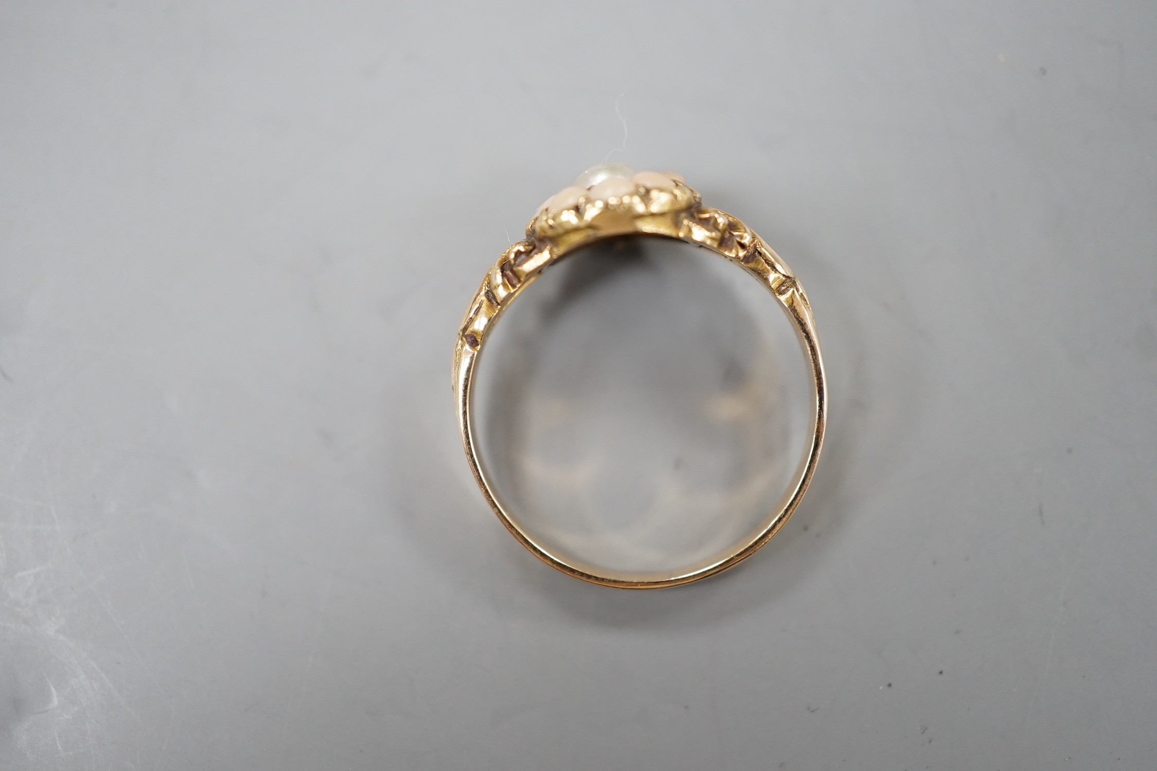 An early 20th century yellow metal, split coral and split pearl cluster set ring, size P, gross weight 2.5 grams.